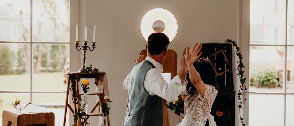 Les mariés posent devant la borne photo, les bras levés