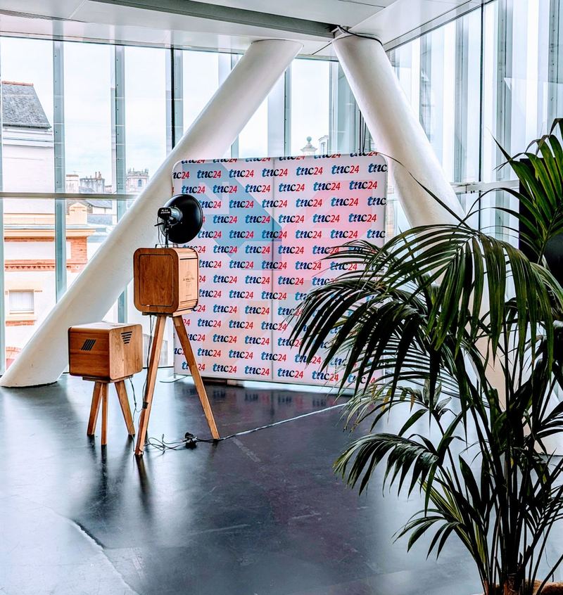 La borne devant un photocall aux couleurs d'une entreprise, dans un espace vitré