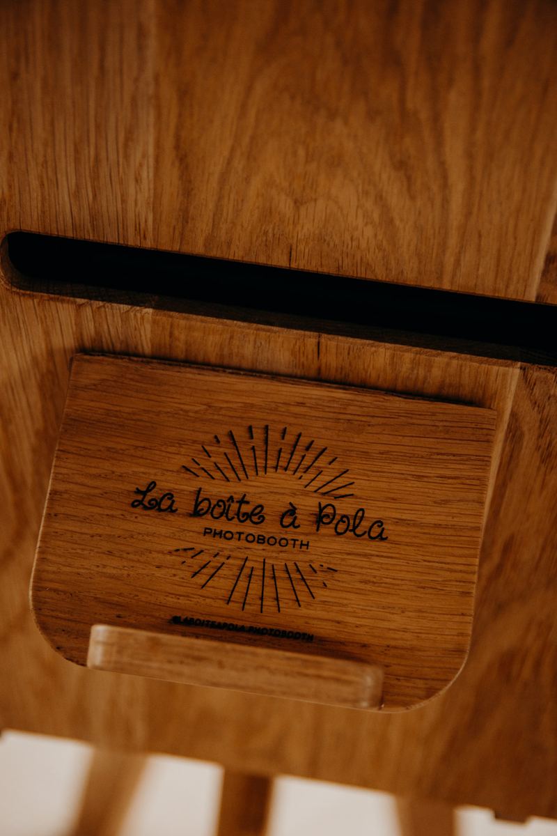 Le logo La Boîte à Pola gravé dans le bois de la borne, au-dessus de la fente d'impression