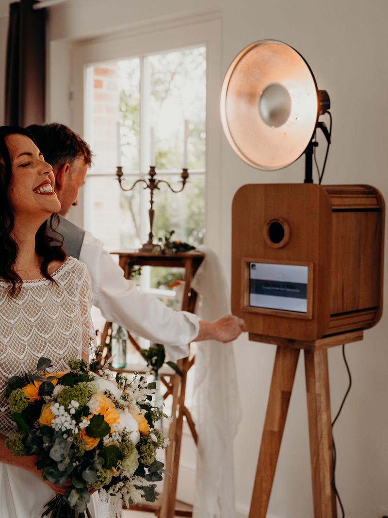 Des mariés éclatent de rire devant la borne photo